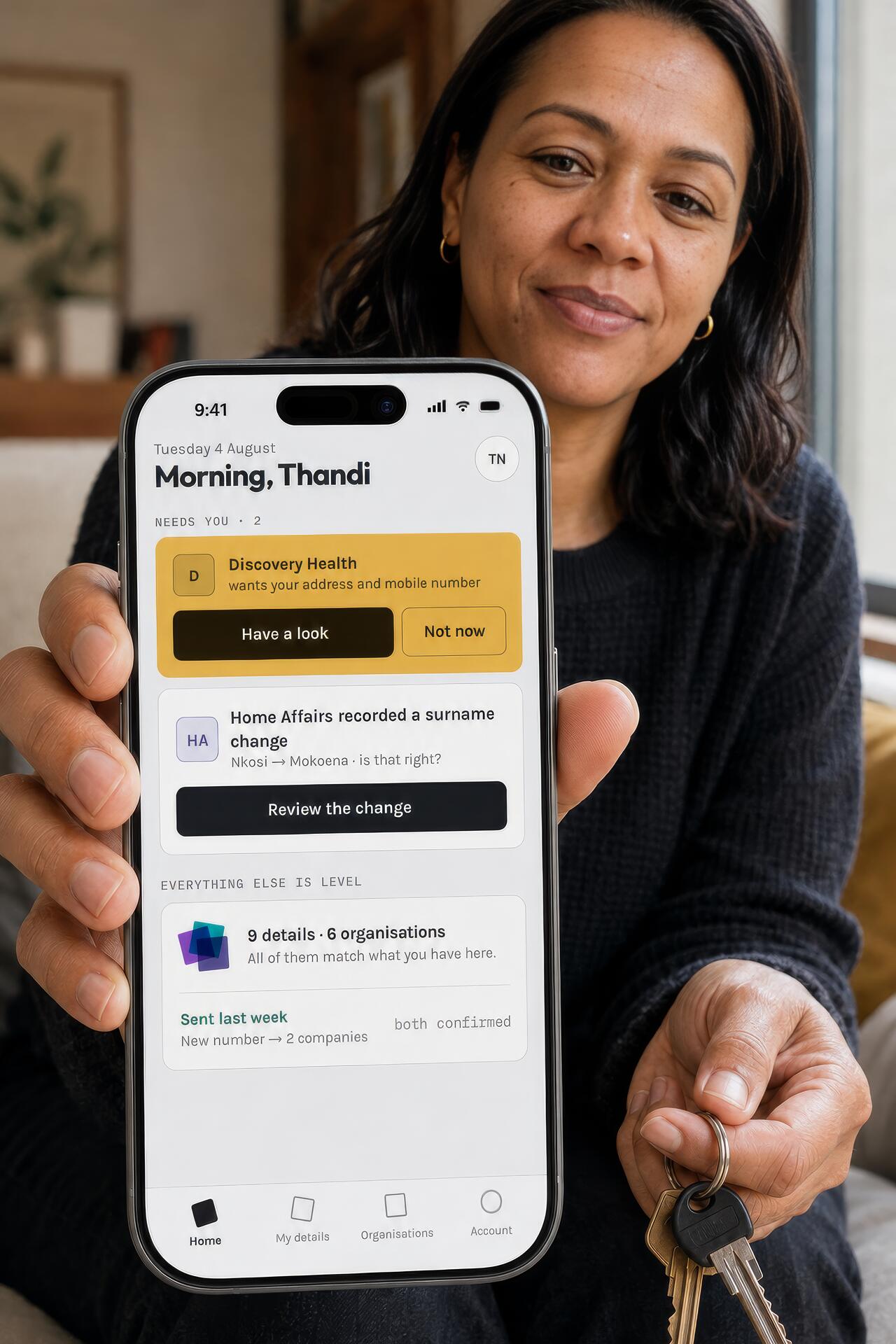 A woman holding up her phone, showing the SameMe home screen with two things waiting for her